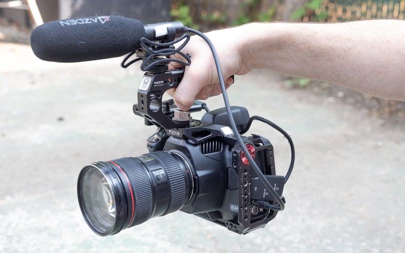 A hand holding the Blackmagic Pocket Cinema Camera 6K G2 in a cage with a mic.