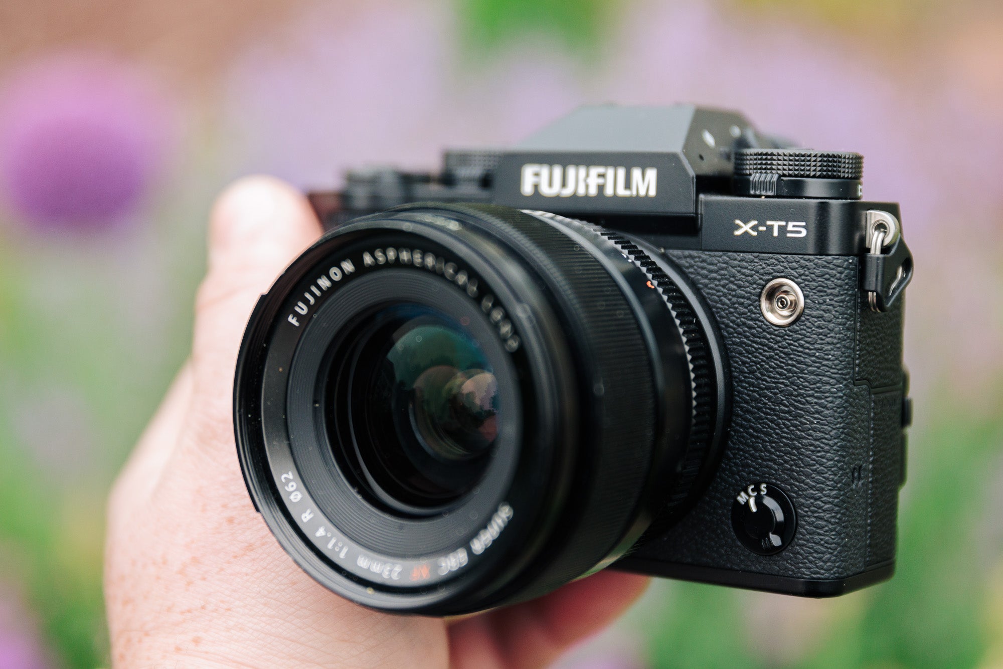 Fujifilm X-T5 in front of blurry flowers at an angle