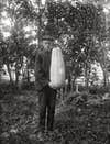 A B&W image of a man with a very large gourd. 