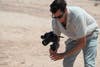 A man holds the Nikon Z f on a gimbal against a sandy background